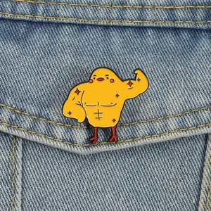 Funny cartoon yellow muscular chicken enamel pin on blue denim fabric background