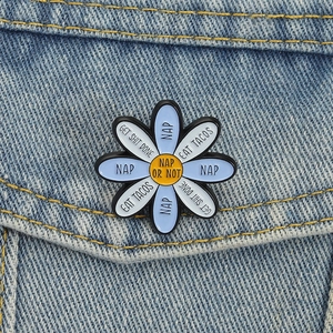 Cute blue daisy enamel pin with funny task choices pinned on a denim jacket pocket