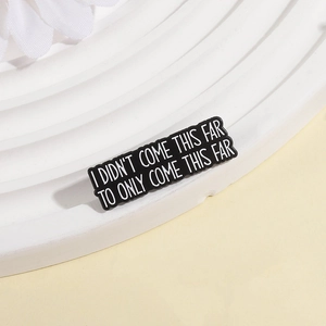 Inspirational enamel lapel pin with white text on black background on white pedestal