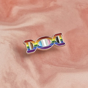 Macro detail of rainbow enamel DNA double helix brooch with polished metal edges