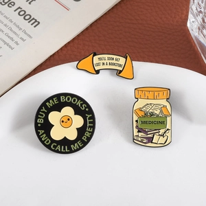 Three literary enamel pins with book quotes on a white plate with aesthetic background