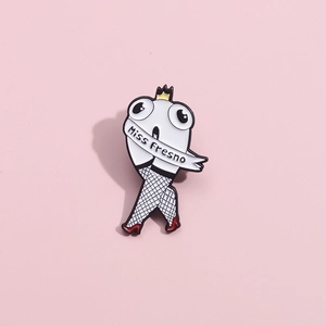 Funny tooth enamel pin wearing a crown and Miss Fresno sash with high heels on pink backdrop