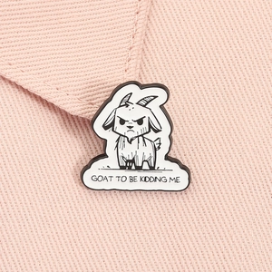 Detail of funny goat enamel pin with GOAT TO BE KIDDING ME text on pink denim fabric