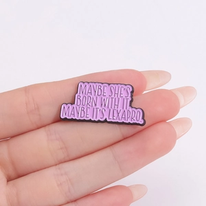 Funny purple enamel pin with Lexapro slogan held by hand against a white background