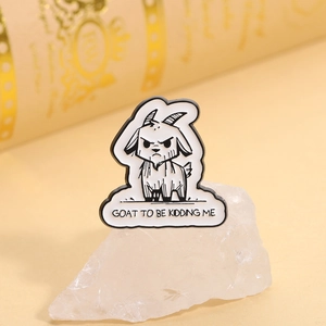 Detail of goat enamel pin with GOAT TO BE KIDDING ME text on white stone prop