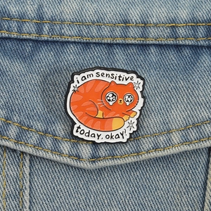 Broche en émail chat orange triste sur veste en jean bleue avec texte humoristique