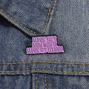 Pink enamel Lexapro slogan badge pinned on a blue denim jacket collar