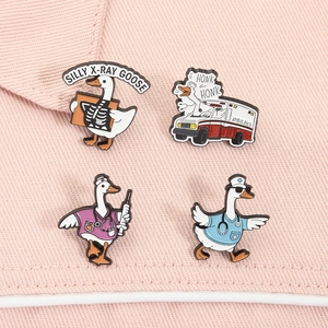 Detail von vier medizinischen Cartoon-Gans-Emaille-Pins auf rosa strukturiertem Hintergrund