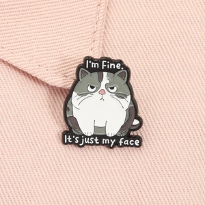 Detail of cartoon grumpy cat enamel pin with I'm Fine text on pink fabric background