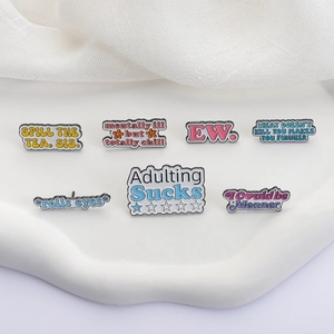 Detailed view of colorful enamel slogan pins with witty English phrases on white waves