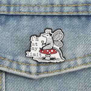 Pin's émaillé fée opossum humoristique avec texte sur fond de veste en jean bleue