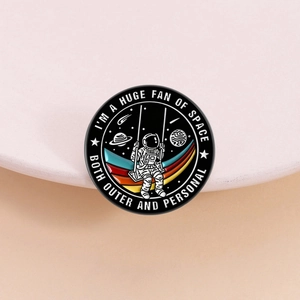 Emaille-Anstecknadel mit Astronaut auf Schaukel und kreativen Weltraum-Zitaten im runden Design