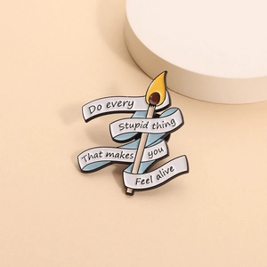 Cartoon matchstick enamel pin with inspirational quote on white ribbon over beige backdrop