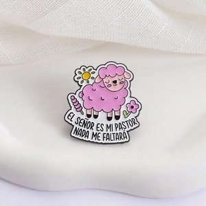 Cartoon pink sheep enamel pin with Spanish biblical text and floral motifs on white background