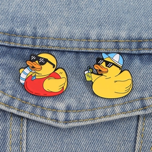 Cute set of two cartoon yellow duck enamel pins on blue denim jacket for summer style