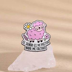 Broche agneau rose mignon avec soleil et fleurs posée sur une pierre blanche