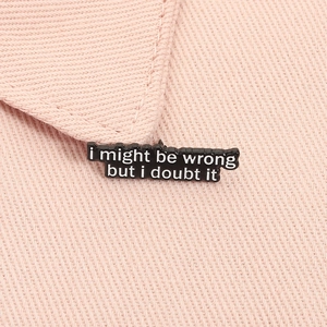 Close-up of black enamel pin with I Might Be Wrong slogan on pink fabric clothing