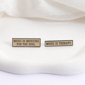 Minimalist enamel music quote brooches on tray with soul medicine and therapy text