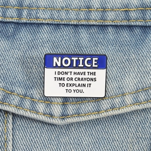 Blue and white 'Notice' enamel pin with humorous text pinned on denim jacket