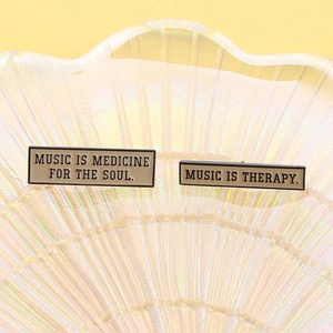 Dettaglio di spille in smalto Music Therapy su vassoio di vetro iridescente e lega liscia