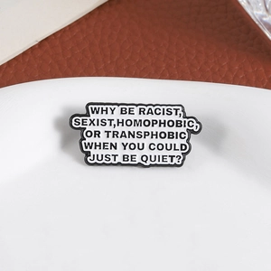 Macro shot of anti-discrimination enamel pin with bold lettering on white plate
