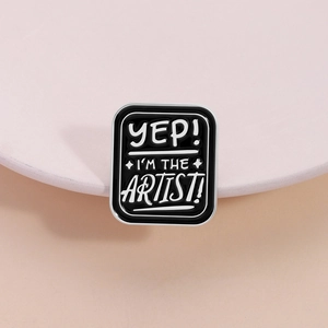 Enamel lapel pin with black background and white Yep I'm The Artist text design