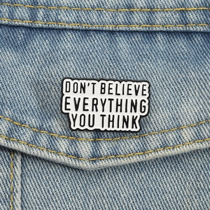 Enamel slogan brooch Don't Believe Everything You Think pinned on blue denim jacket