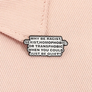 Macro shot of an anti-discrimination enamel brooch on pink denim fabric surface