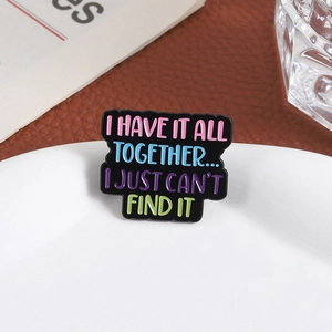 Détail d'un pin's humoristique en émail avec lettres colorées sur une assiette en céramique