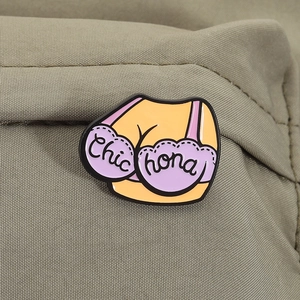 Macro shot of an enamel pin featuring a purple bra design on textured khaki fabric