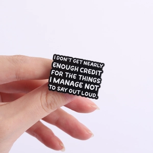 Detail of humorous enamel pin with wave border held by hand showing actual scale and text