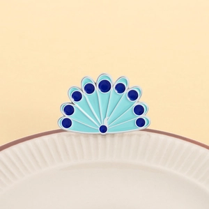 Détail macro d'une broche éventail plume de paon en émail bleu sur plat céramique