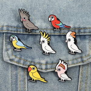 Set of seven colorful cartoon parrot enamel pins displayed on a blue denim pocket jacket