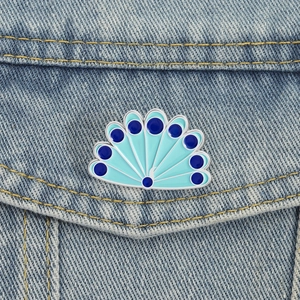 Broche paon en émail bleu pour un style créatif sur une poche de veste en jean