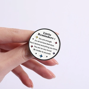 Inspirational metal pin with Little Reminders quote and colorful stars on a white base