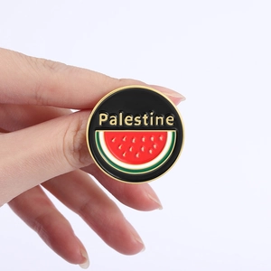 Macro shot of a round Palestine enamel pin with watermelon pattern and golden edges