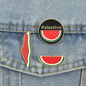 Three-piece watermelon enamel pin set with gold trim on a blue denim background