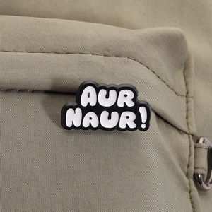 Macro shot of AUR NAUR! black and white enamel pin on olive green canvas bag