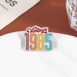 Retro Vintage 1985 enamel pin with colorful stripes on a white ceramic plate