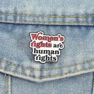 Minimalist enamel brooch with Women's rights are human rights slogan on denim jacket