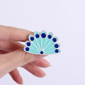 Vue à la main d'une broche en émail plume de paon bleu avec détails en métal argent