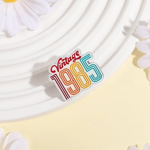 Retro 1985 Vintage enamel metal brooch badge with colorful stripes on a display stand
