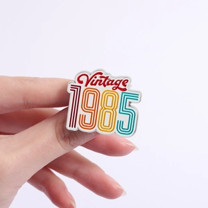 Close-up of a vintage 1985 enamel brooch with colorful stripes held by hand