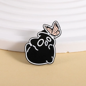 Close-up of black soot sprite enamel pin featuring a pink butterfly on geometric background