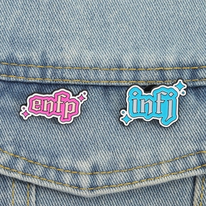 Cute MBTI personality enamel pins featuring ENFP and INFJ designs on denim jacket