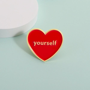 Red heart enamel brooch with gold 'yourself' lettering on a light green background