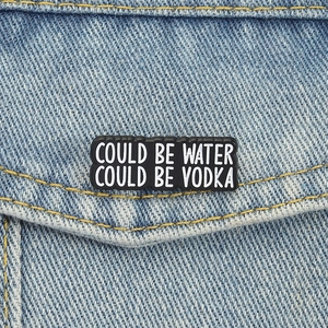 Spilla in smalto nero con scritta Could Be Water Could Be Vodka su giacca denim