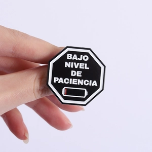Détail de la broche octogonale avec texte Low Patience et icône batterie rouge