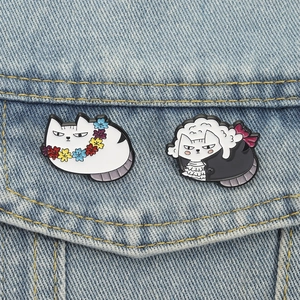 Gentleman cat and flower wreath cat enamel pins displayed on blue denim jacket