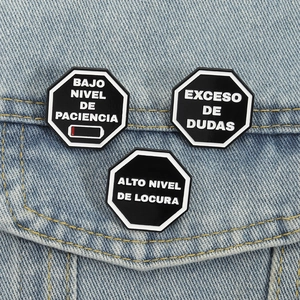 Lot de trois broches en émail avec texte espagnol portées sur une veste en denim